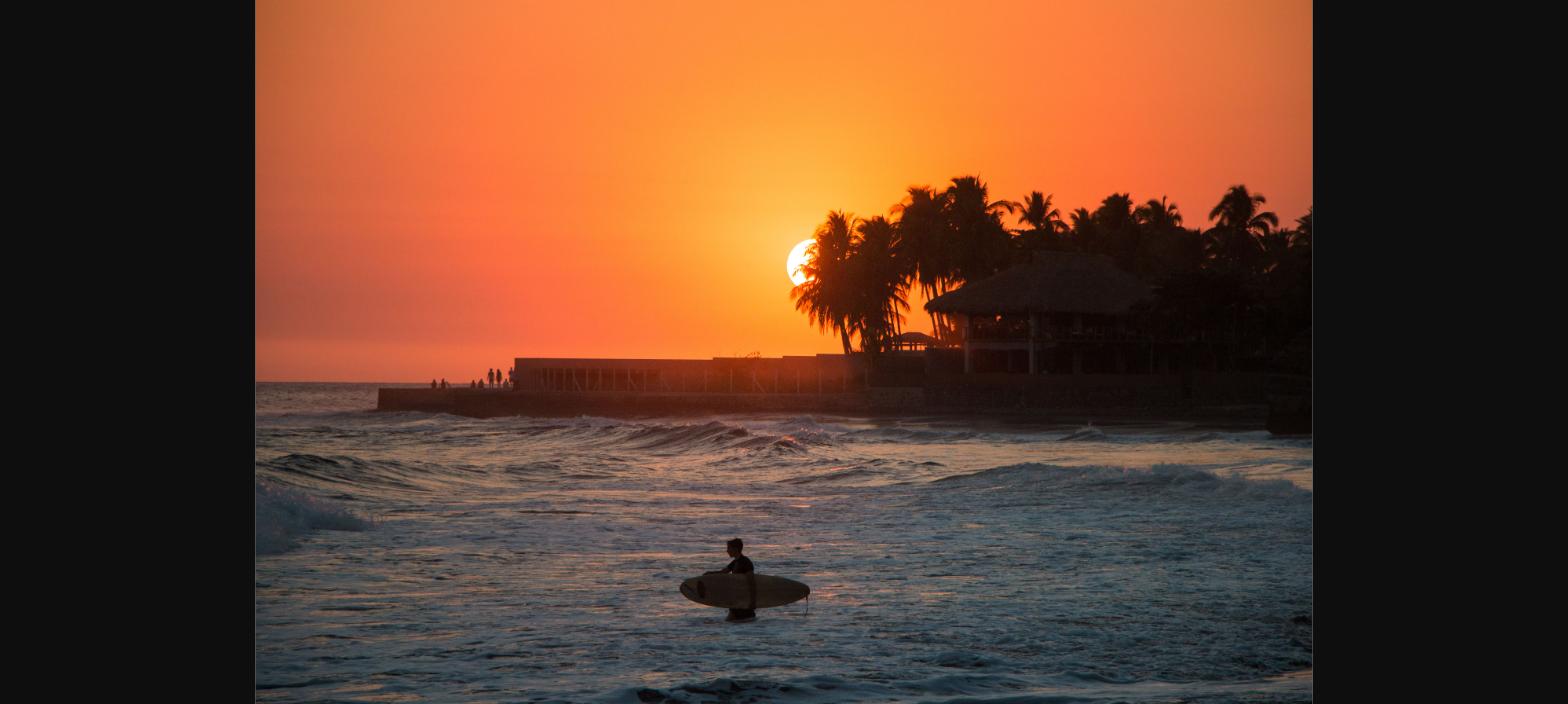 Surfer at sunset on El Salvador Pacific coast - Montano & Company attorneys